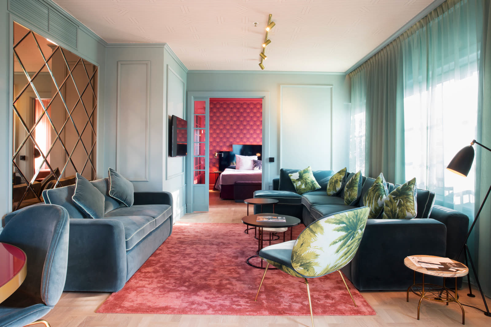 Suite lounge with teal velour sofas and palm-patterned chairs