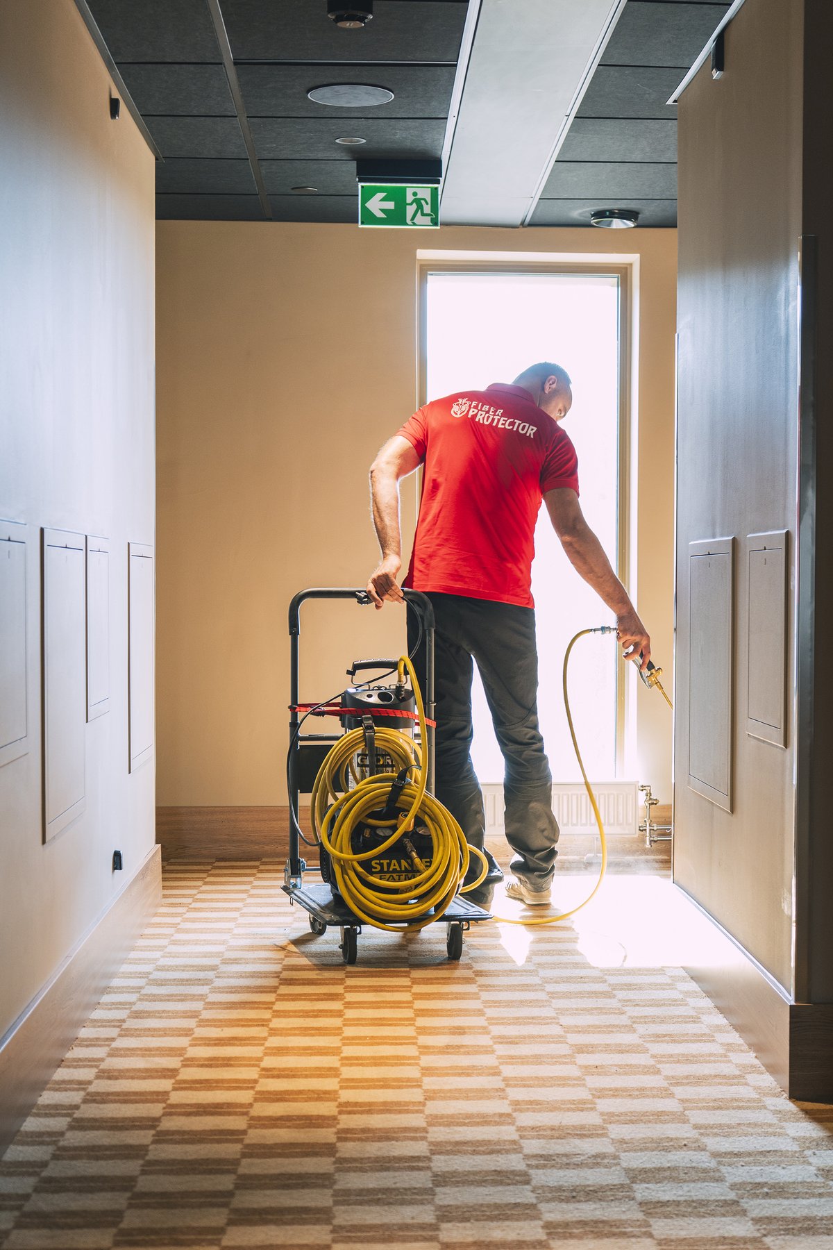 Fiber ProTector technician impregnating carpet in a hotel corridor