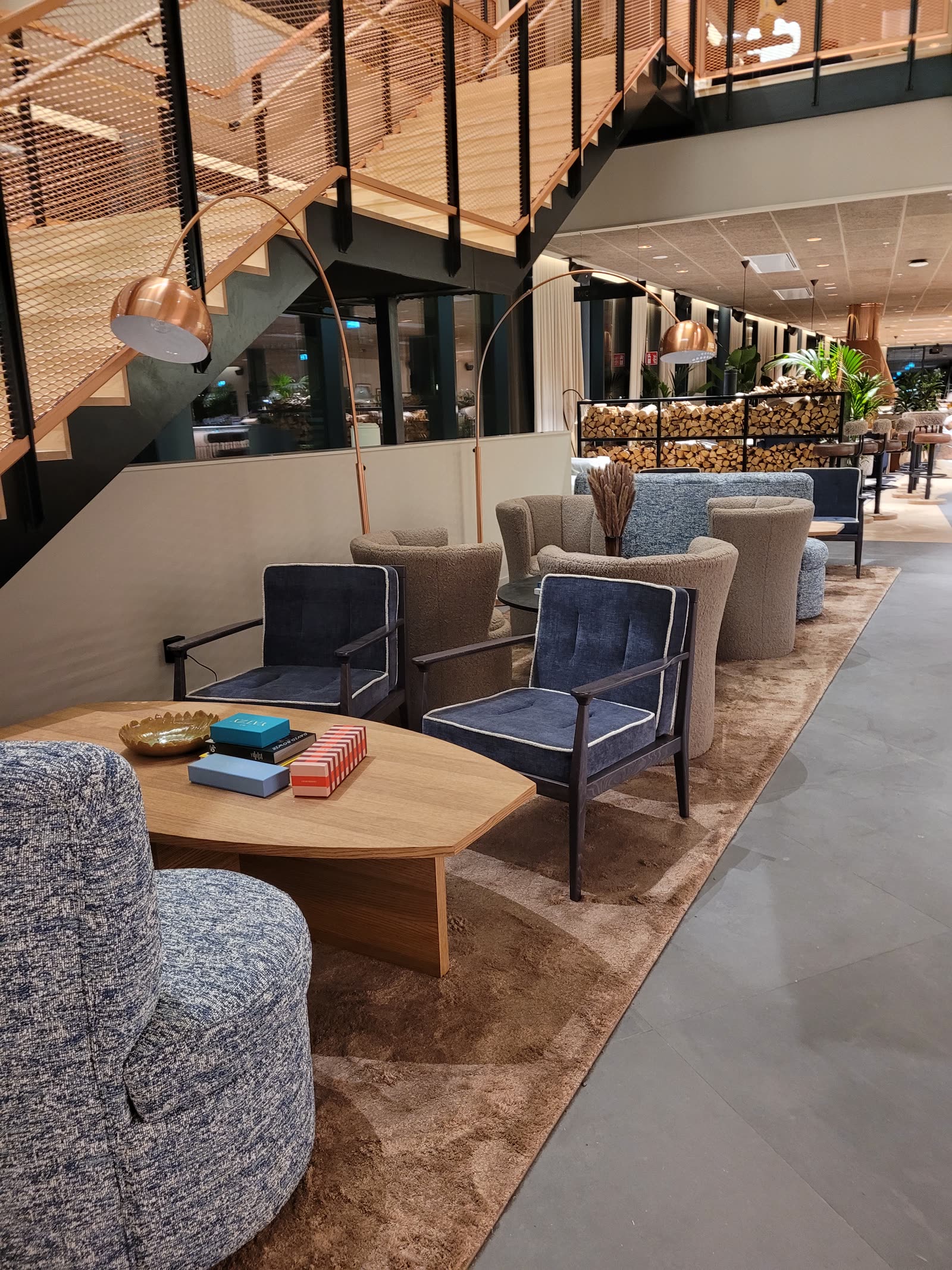Hotel lobby with blue velour chairs and boucle sofas under copper lamps
