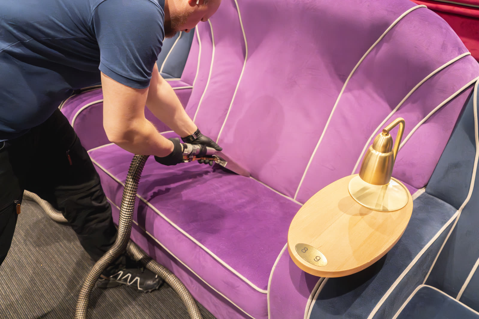 Fiber ProTector technician deep cleaning a violet velour sofa in a cinema