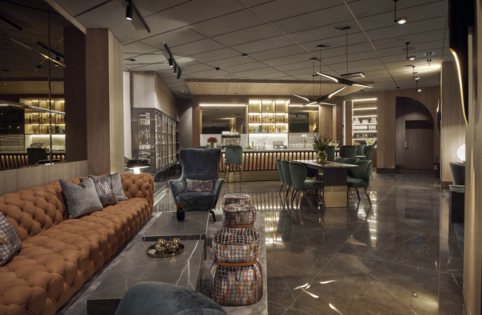 Marble bar lounge with curved velour sofa and crocodile-skin ottomans