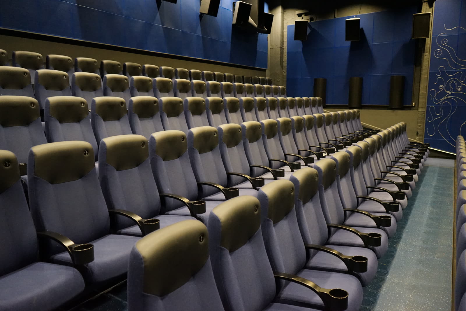 Grey-blue cinema seats with leather headrests in a modern auditorium