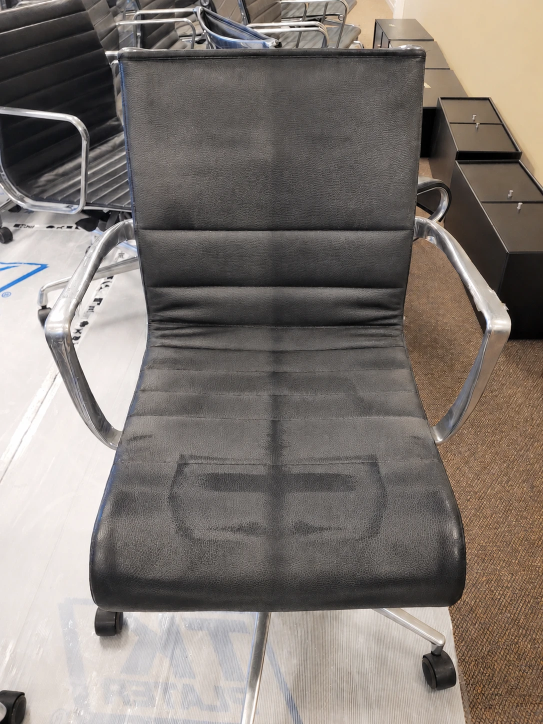 Before treatment — black leather chair with wear and cracks
