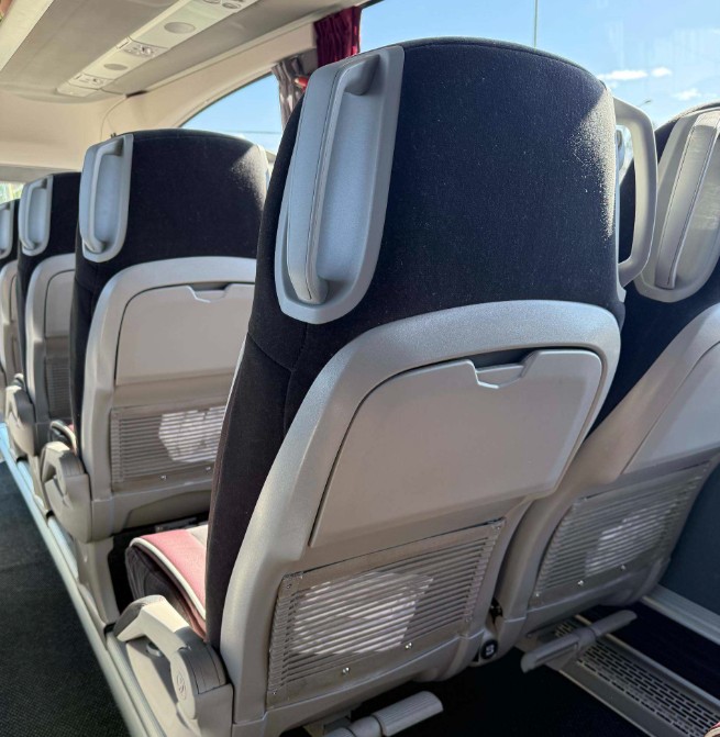 Rows of bus seats with dark fabric covers and light headrests